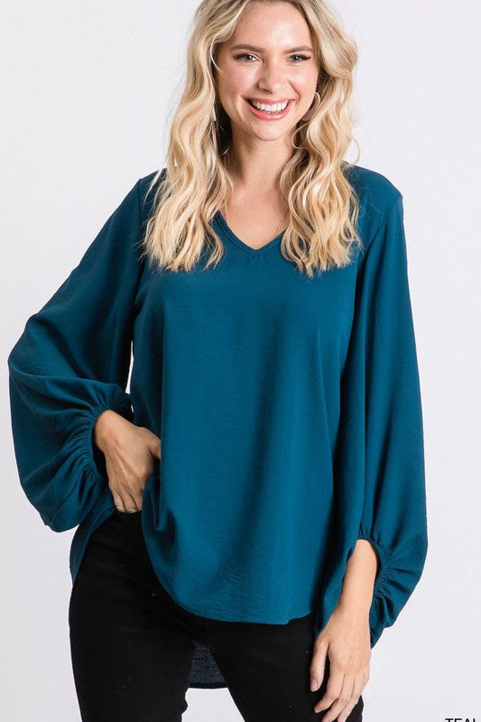Woman wearing a teal blouse with a plain background